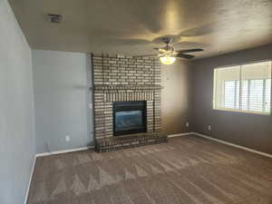 Unfurnished living room featuring carpet flooring, baseboards, and a ceiling fan