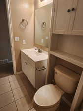 Half bath with tile patterned flooring, visible vents, toilet, vanity, and baseboards