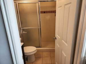 Bathroom featuring tile patterned flooring, toilet, and walk in shower