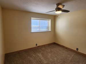 Spare room featuring carpet flooring, baseboards, and a ceiling fan
