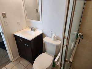 Bathroom featuring tile patterned flooring, vanity, toilet, and walk in shower