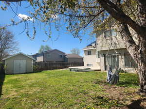 View of yard with fence, a storage unit, an outbuilding, and a deck
