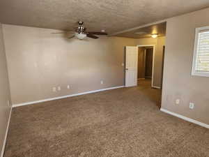 Spare room with carpet, a textured ceiling, baseboards, and ceiling fan