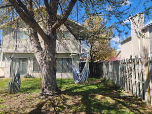 Rear view of house with a fenced backyard and a lawn