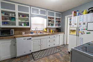 Kitchen featuring white cabinetry, sink, backsplash, white appliances, and a textured ceiling