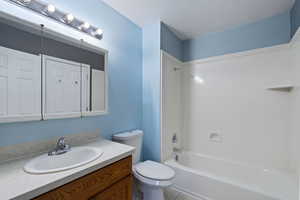 Full bathroom with tub / shower combination, vanity, a textured ceiling, tile patterned floors, and toilet