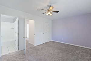 Unfurnished bedroom featuring ceiling fan and light colored carpet
