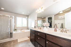 Primary onsuite with double sinks, tile flooring, shower with separate soaker bathtub and large vanity.