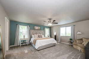 Oversized Primary Bedroom with lots of windows for natural daylight, carpet flooring and ceiling fan.