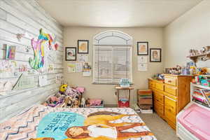 Bedroom with light colored carpet and a textured ceiling