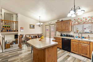 Kitchen featuring sink, hanging light fixtures, black dishwasher, a notable chandelier, and a kitchen island