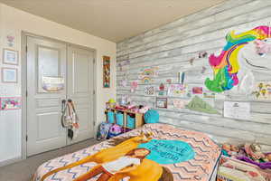 Carpeted bedroom featuring a textured ceiling and a closet