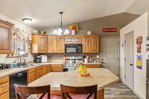 Kitchen with lofted ceiling, sink, decorative light fixtures, a chandelier, and black appliances