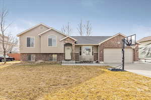 Split level home with a garage, a front yard, and a patio area