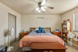 Bedroom with ceiling fan, carpet, and a textured ceiling