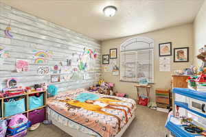 Bedroom with light colored carpet and a textured ceiling