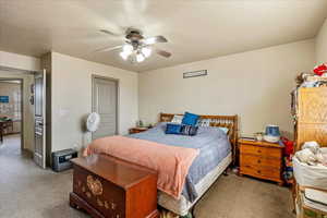 Carpeted bedroom with ceiling fan and a textured ceiling