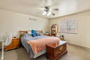 Carpeted bedroom featuring a textured ceiling and ceiling fan