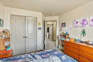 Carpeted bedroom featuring a closet and a textured ceiling