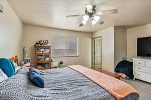 Bedroom with ceiling fan, carpet, and a textured ceiling