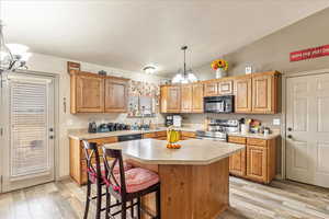 Kitchen featuring pendant lighting, lofted ceiling, a center island, an inviting chandelier, and electric stove