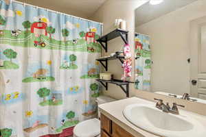 Bathroom with vanity, a textured ceiling, toilet, and walk in shower