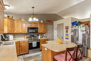 Kitchen featuring sink, stainless steel appliances, a kitchen island, decorative light fixtures, and a chandelier