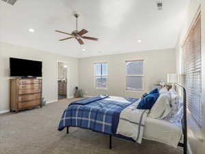 Bedroom with ceiling fan, light colored carpet, and ensuite bath