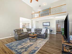 Living room with ceiling fan, a towering ceiling, and dark hardwood / wood-style floors