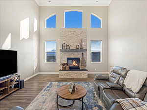 Living room featuring dark hardwood / wood-style flooring, crown molding, a fireplace, and a towering ceiling