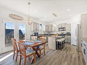 Dining area with wood-type flooring, a notable chandelier, and french doors