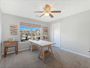 Carpeted home office featuring ceiling fan