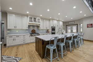 Kitchen with white cabinetry, appliances with stainless steel finishes, a kitchen breakfast bar, and a spacious island