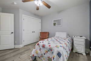 Bedroom featuring ceiling fan, light wood-type flooring, and a closet