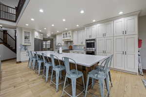 Kitchen featuring a large island with sink, appliances with stainless steel finishes, a breakfast bar, and light wood-type flooring