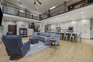 Living room featuring a towering ceiling, light hardwood / wood-style flooring, and ceiling fan