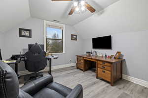 Home office featuring vaulted ceiling, ceiling fan, and light hardwood / wood-style flooring