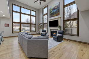 Living room with a high ceiling, ceiling fan, and light hardwood / wood-style flooring