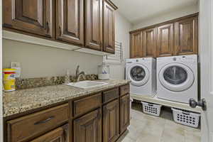 Laundry area with cabinets, separate washer and dryer, sink, and light tile patterned floors