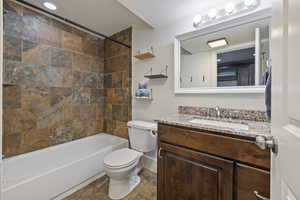 Full bathroom featuring tiled shower / bath, vanity, and toilet