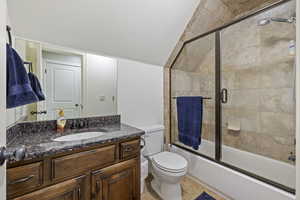 Full bathroom with toilet, vanity, and shower / bath combination with glass door