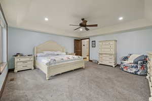 Bedroom featuring a tray ceiling, carpet floors, and ceiling fan