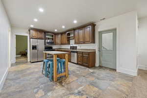 Kitchen featuring a kitchen island, appliances with stainless steel finishes, sink, and a kitchen breakfast bar