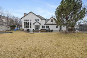 Rear view of house with a yard, a hot tub, a playground, and a patio area