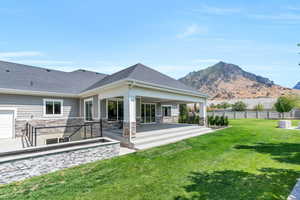 Back of property with a patio, a mountain view, and a yard