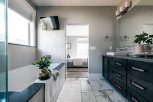 Bathroom featuring vanity, a tub to relax in, and tasteful backsplash