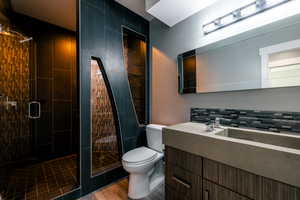 Bathroom featuring a shower with shower door, tasteful backsplash, hardwood / wood-style flooring, vanity, and toilet