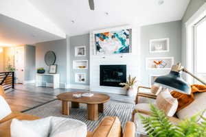 Living room with lofted ceiling, built in features, and a fireplace