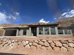 Rear view of house with stucco siding, a mountain view, stone siding, and a garage
