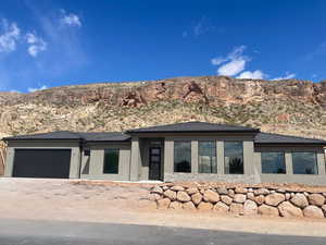Prairie-style home featuring driveway, stone siding, a mountain view, an attached garage, and stucco siding